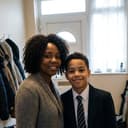 A mum in the hallway with her hand on the shoulder of her son, who is in school uniform.